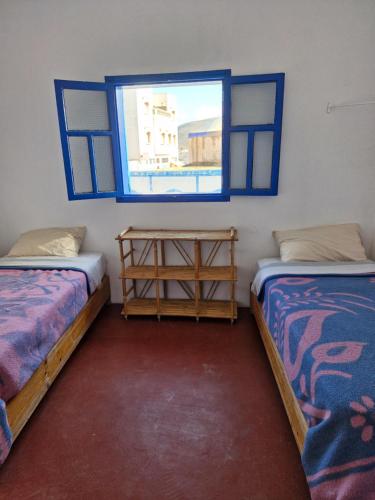 two beds in a room with a window at le grand atlas in Mirleft
