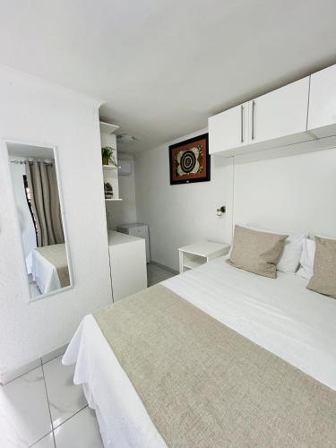 a white bedroom with a bed and a mirror at Duvha Guesthouse in Graskop