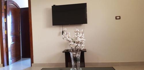a vase of flowers sitting on a table with a tv at El BOB HOUSE in Luxor