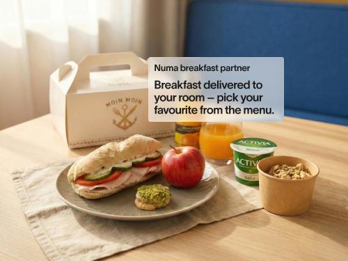 Ein Teller mit einem Sandwich und einem Apfel auf einem Tisch in der Unterkunft Numa Hamburg St Georg in Hamburg