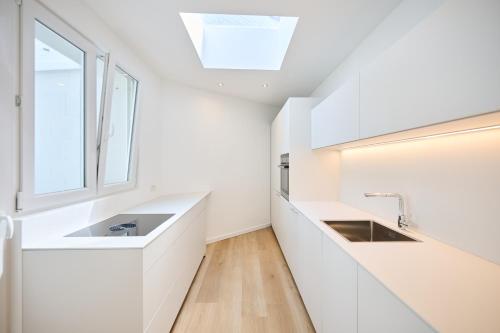 a white kitchen with two sinks and a window at Toison d'Or & saunna 2 in Brussels