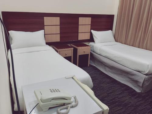 a room with two beds with a phone on it at فندق الواحة الماسية 2 in Al Khansāk