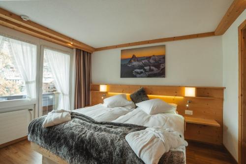 a bedroom with a large bed with white sheets and pillows at Hotel Matterhornblick in Zermatt