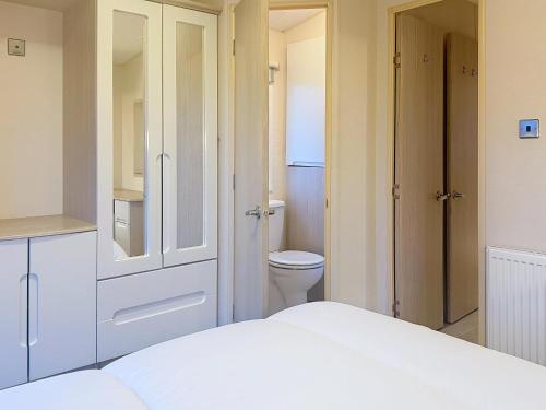 una camera da letto bianca con un bagno e un letto di Dog Friendly 6 Berth Caravan With Decking Close To Pakefield Beach Ref 68067B a Pakefield