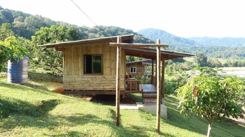 een klein houten huis op een heuvel met een boom bij Chanya homestay in Ban Yang