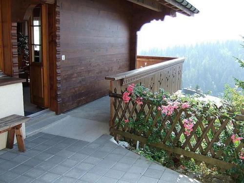 a porch of a house with a wooden fence and flowers at Apartment Chalet Hofer by Interhome in Hasliberg Wasserwendi