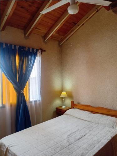een slaapkamer met een bed met een blauw gordijn en een raam bij PH Santa Teresita in Santa Teresita