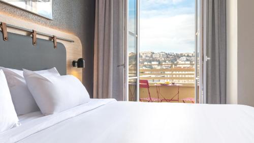 een slaapkamer met een bed en een groot raam bij Campanile PRIME - Lyon Centre - Gare Perrache in Lyon