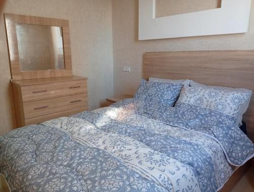 a bedroom with a bed with a blue comforter and a mirror at Cozy and Comfortable Apartment in Agadir