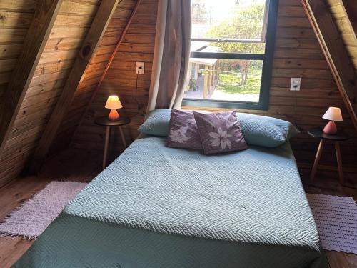 un letto in una camera con finestra e due lampade di Cabana Itapeva Torres a Torres