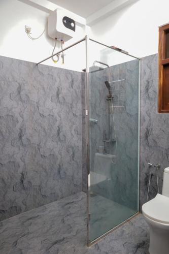 a shower with a glass door in a bathroom at Solomon Beach Hotel in Marawila