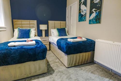 twee bedden in een slaapkamer met blauwe muren bij Mayfield House in Newtongrange