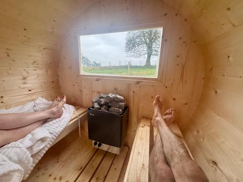 Twee mensen in een sauna met hun voeten op het bed. bij Winter Recharge - Secluded Luxury Cabins with stream, stargazing, bookable sauna, walks and nature - Fell Farm Hideaway in Colwell
