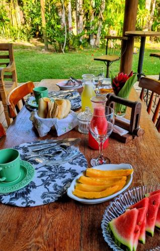 a wooden table with plates of food and fruit on it at Vila Pitanga Trancoso in Trancoso