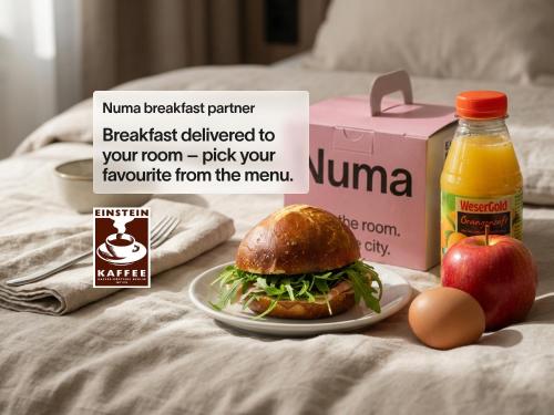 a sandwich on a plate with an apple and a box of juice at Numa Berlin Nook in Berlin