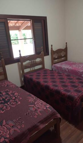 a bedroom with two beds and a window at Sítio flor do campo 7L in Sete Lagoas