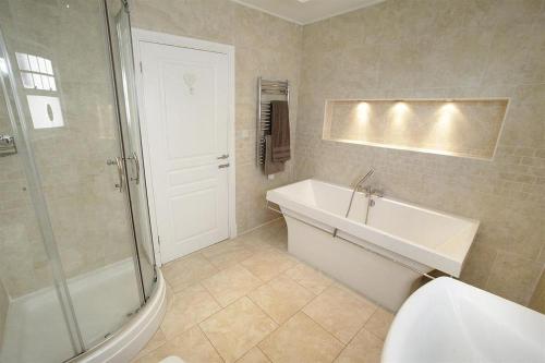 a bathroom with a tub and a shower and a sink at 4 Bed in Gower oc-hh672 in Port-Eynon