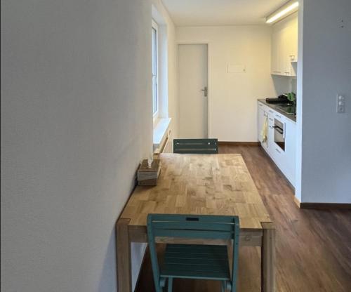 eine Küche mit einem Holztisch und einem grünen Stuhl in der Unterkunft Satin Home in Savognin
