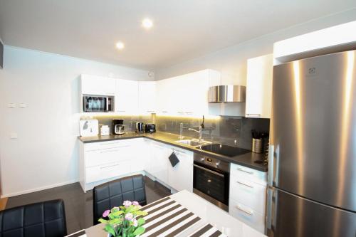 a kitchen with white cabinets and a stainless steel refrigerator at Santalux Apartment in Rovaniemi