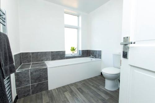 a bathroom with a tub and a toilet and a window at K Suites - Granville Avenue in Long Eaton