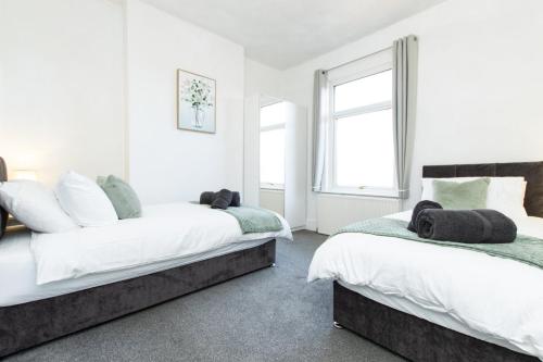 two beds in a room with white walls and windows at K Suites - Granville Avenue in Long Eaton