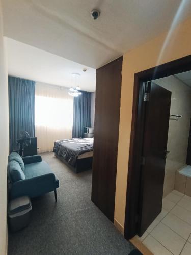 a hotel room with a bed and a couch and a mirror at ApartHotel Rooms in Ajman