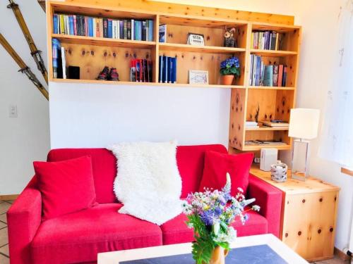 a red couch in a living room with a book shelf at Apartment Curtins18 by Interhome in Pontresina