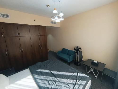 a bedroom with a bed and a blue chair at ApartHotel Rooms in Ajman