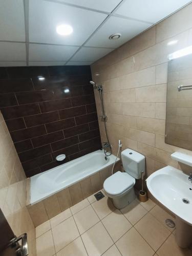 a bathroom with a toilet and a tub and a sink at ApartHotel Rooms in Ajman
