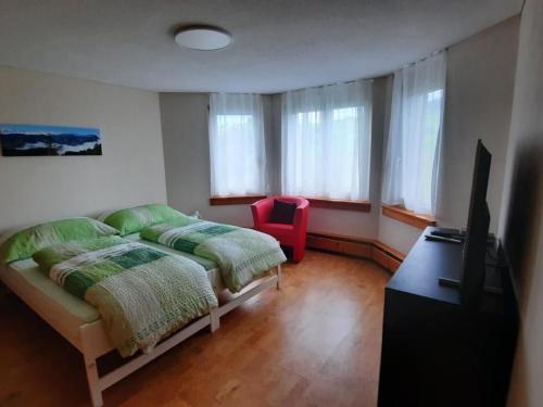 a bedroom with a bed and a television and a chair at Apartment Angenweg 2 by Interhome in Entlebuch