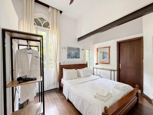 een witte slaapkamer met een bed en een spiegel bij Semiramis Boutique Hotel & Spa in Kato Platres