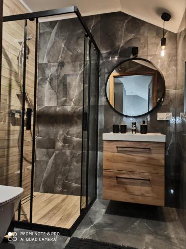 a bathroom with a shower and a sink and a mirror at Apartament Górska Przystań Kluszkowce in Kluszkowce