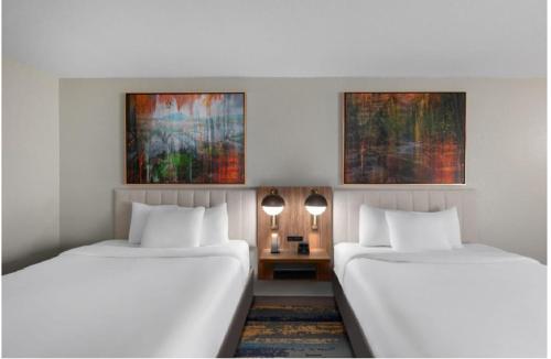 two beds in a room with two lamps and a table at La Quinta by Wyndham Knoxville Central Papermill in Knoxville