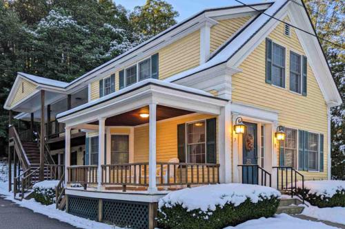 a yellow house with a porch in the snow at Champagne Supernova in Ludlow