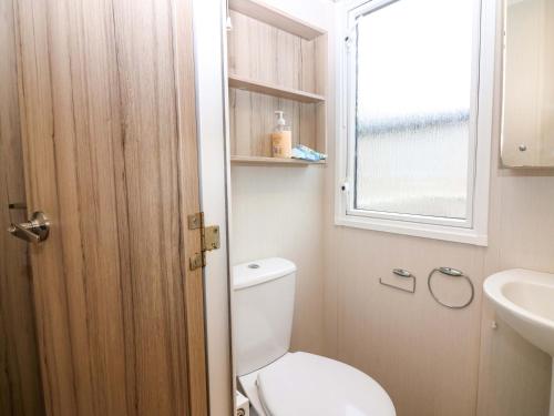 a bathroom with a toilet and a sink and a window at Caravan number 77 in Eyemouth