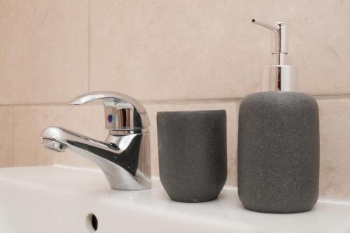 un lavabo de salle de bain avec un distributeur de savon à côté d'un robinet dans l'établissement K Suites - Fulbridge Road 116, à Paston