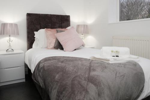 une chambre avec un grand lit blanc avec des oreillers roses dans l'établissement K Suites - Fulbridge Road 116, à Paston