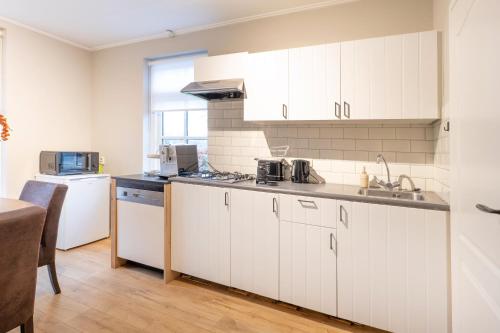 a kitchen with white cabinets and a sink at Aan `t Krakeel in Noordscheschut