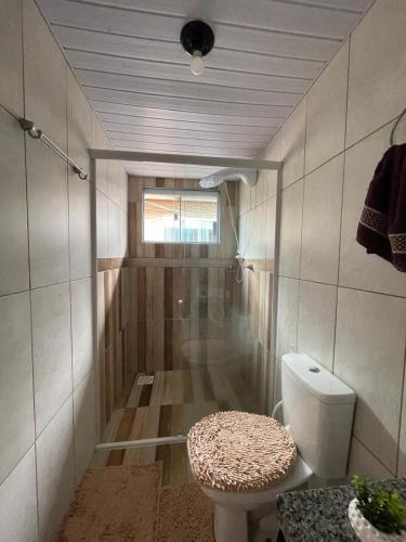 a small bathroom with a toilet and a window at Riba Brisa in Imbituba