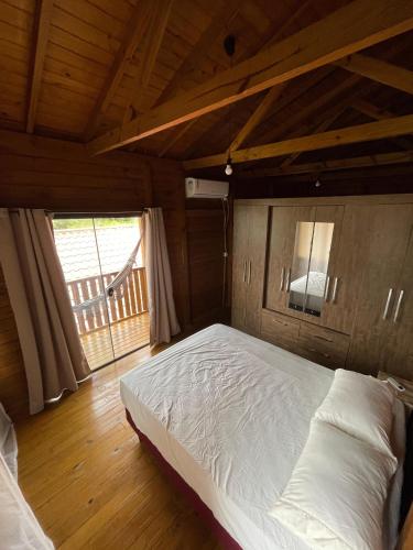 a bedroom with a white bed in a wooden room at Riba Brisa in Imbituba