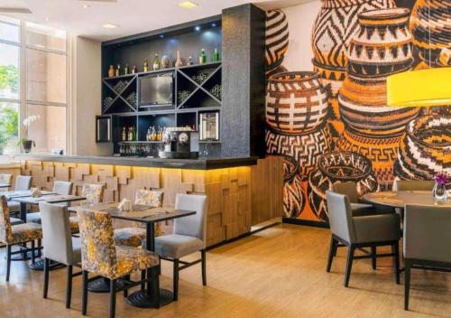 ein Restaurant mit Tischen und Stühlen und eine Bar in der Unterkunft GRU Airport Easy Stay in Guarulhos
