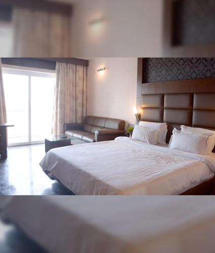 a hotel room with a large bed and a couch at Hotel Tazzodisha Next in Bhubaneshwar