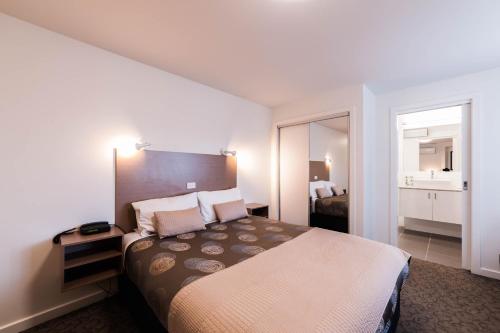 Habitación de hotel con cama y espejo en Eastern Sands City Centre, en Geelong