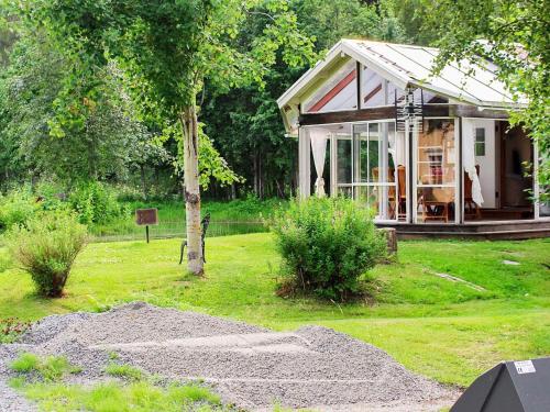 een klein huis in een tuin met gras en bomen bij 9 person holiday home in KÄLARNE in Kälarne