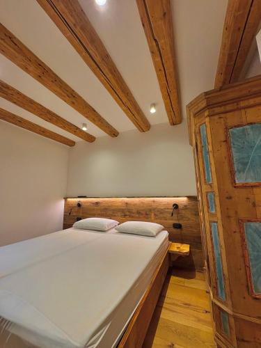 een slaapkamer met een bed in een kamer met houten plafonds bij Casa Patty Moena in Moena