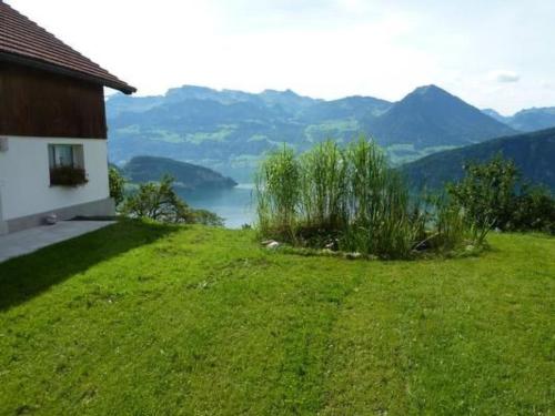 a grassy hill with a house and mountains in the background at Apartment Oberwilen by Interhome in Vitznau