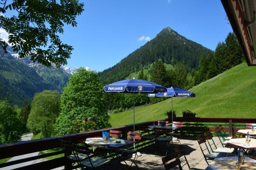 a table with an umbrella on a balcony with mountains at Hotel Tiroler Herz in Hinterhornbach