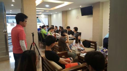 een groep mensen die aan een tafel in een kamer zitten bij Pandora Motel in Yangon