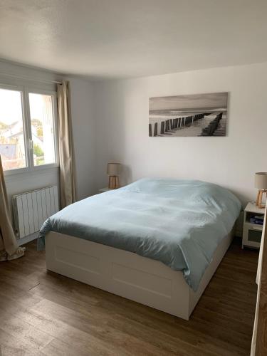 a white bedroom with a bed with blue sheets at Appartement Carnac, Centre bourg - 2 pieces in Carnac
