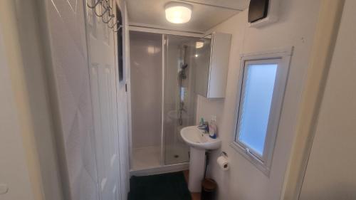 een witte badkamer met douche en wastafel bij RBR 662 - Beach Resort Kamperland in Kamperland